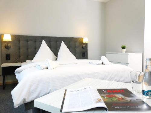 a hotel room with two beds and a book on a table at Residence Aparthotel in Szczecin