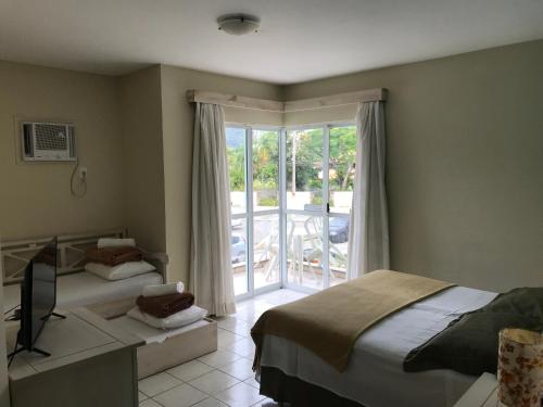 a bedroom with two beds and a sliding glass door at Pousada Vila Verde in Porto Belo