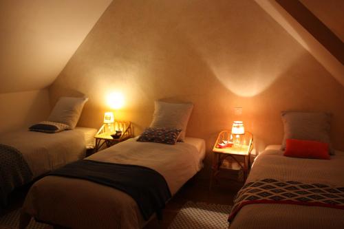 Logonna-DaoulasにあるLes gites d'Hellenの照明付きの部屋にベッド3台が備わる部屋