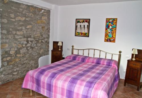 a bedroom with a bed with a purple plaid blanket at I Poggi di Grace in Fivizzano