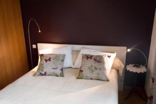 una camera con un letto bianco con due cuscini di L'OREE DES BUIS*** a Vouillé