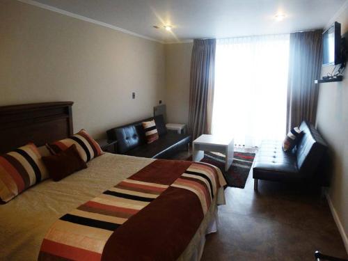 a hotel room with a bed and a couch and a window at Hotel Del Valle Quilimari in Pichidangui