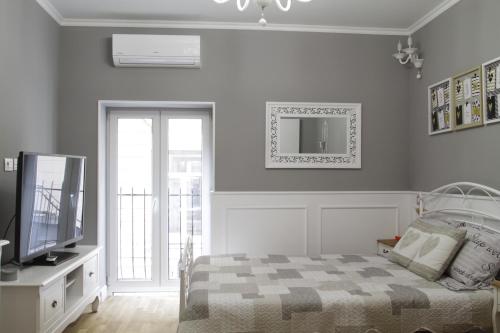 a bedroom with a bed and a tv and a window at Amando Bucharest in Bucharest