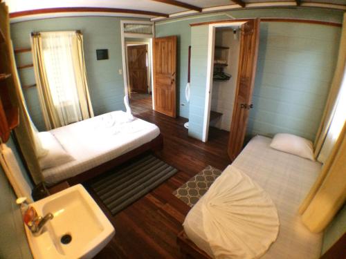 a small room with two beds and a sink at Casa Marbella in Tortuguero