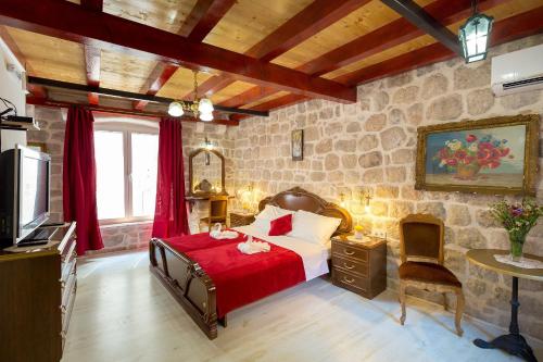 a bedroom with a bed and a tv and a stone wall at Juliette's Palace Studios in Dubrovnik