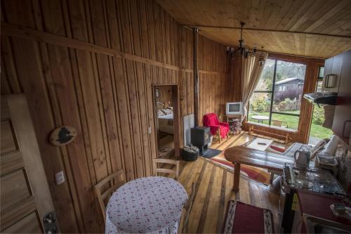 een woonkamer met houten lambrisering en een tafel en stoelen bij Cabañas Entre Verdes in Frutillar