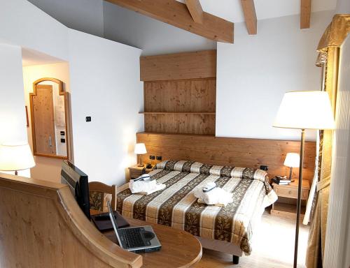 Hotel Al Parco في موينا: غرفة نوم مع سرير وجهاز كمبيوتر محمول على طاولة