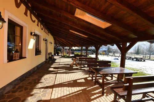 a patio with wooden tables and benches and a building at Villa Victoria Penzion in Liptovský Ján