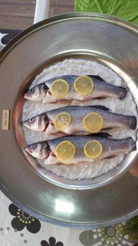 four fish in a pan with lemon slices on them at Apartment Carpe Diem 1 in Utjeha