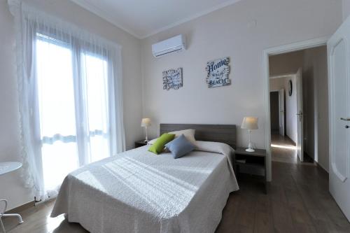 een witte slaapkamer met een bed en een groot raam bij Mavi Apartments in Piano di Sorrento