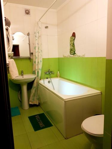 a green bathroom with a tub and a sink at Hotel Om Shanti in Odesa