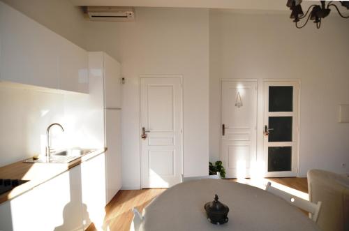 uma cozinha branca com uma mesa e um lavatório em Hanna-Logis em Antibes