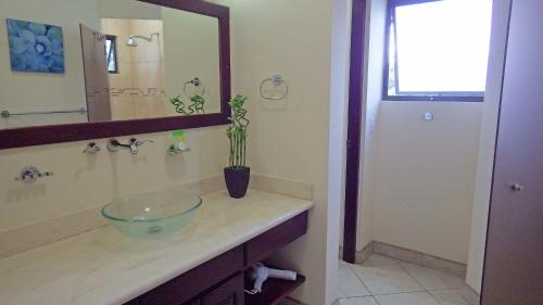 a bathroom with a glass bowl sink and a mirror at The Oaks Tamarindo Pool Front Condominiums fast wifi in Tamarindo