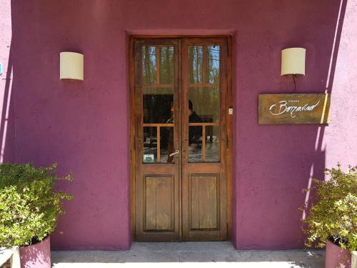 a purple building with a wooden door in front at Posada Borravino in Chacras de Coria