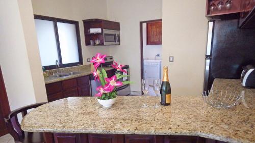a kitchen with a table with a bottle of wine and flowers at The Oaks Tamarindo Pool Front Condominiums fast wifi in Tamarindo