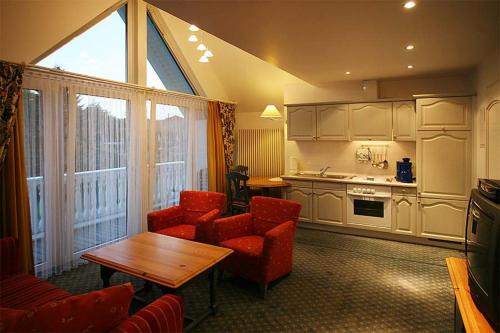 a living room with red chairs and a table and a kitchen at Landhaus Mühlenberg in Willingen