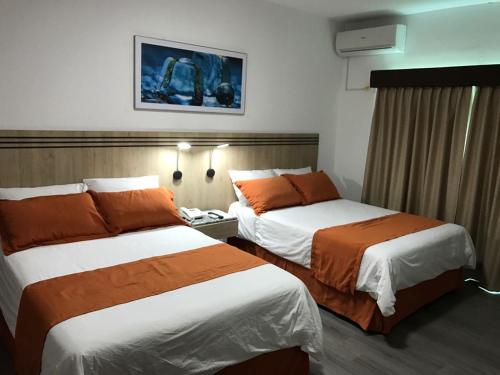 Habitación de hotel con 2 camas con sábanas de color naranja en Hotel Mar Azul en Manta