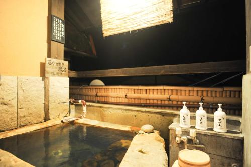 a bath tub with bottles of water in it at Fumoto Ryokan in Minamioguni