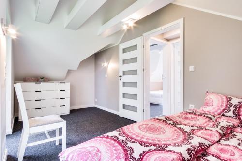 a bedroom with a pink bed and a chair at Domki BOSMAN Lubiatowo in Lubiatowo