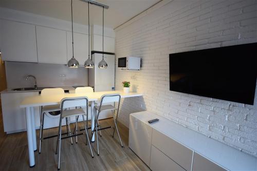 cocina con mesa y sillas y TV en Apartamento Playa Mar, en Castelldefels