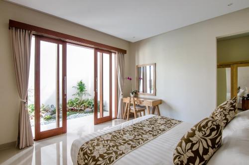 a bedroom with a large bed and a balcony at Kesari Haven in Sanur
