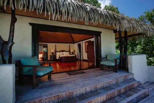 a patio with two chairs and a bed in a room at Pacific Resort Aitutaki - Adults Only in Arutanga