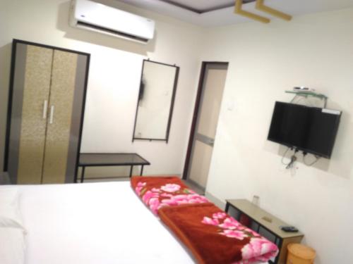 a bedroom with a bed and a tv on the wall at Anand Mahal Hotel in Nagpur