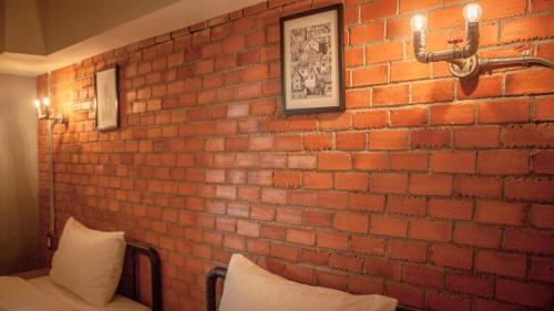 a brick wall in a room with pillows on a bed at The Old Inn in Udon Thani