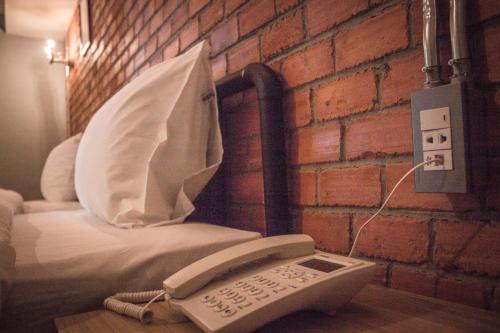 a room with a phone next to a brick wall at The Old Inn in Udon Thani