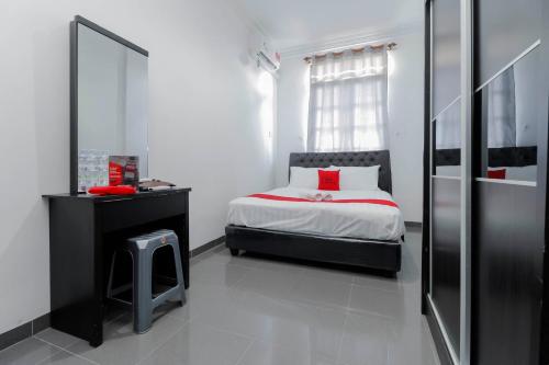 a small bedroom with a bed and a mirror at RedDoorz Plus near Batam City Square in Batam Center