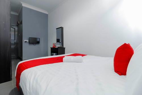 a bedroom with a white bed with red pillows at RedDoorz Plus near Batam City Square in Batam Center