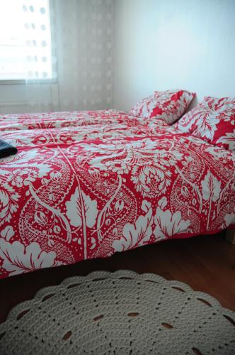 a bed with a red and white comforter on it at Aliisa's Apartment in Rovaniemi