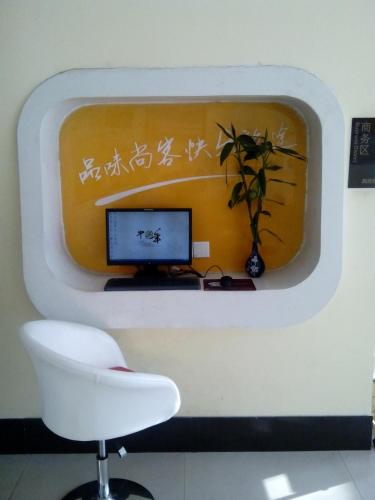 una pared con un monitor, una silla y una planta en Thank Inn Chain Hotel Shandong Rongchengshi Island South Huanghai Road, en Dongshan