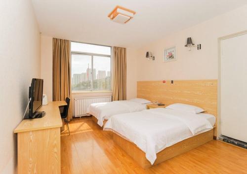 a hotel room with two beds and a television at JUNYI Hotel Shandong Qingdao Huangdao District Shiyou University in Xianlang