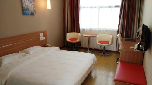 Habitación de hotel con cama, mesa y sillas en Thank Inn Chain Hotel Henan Xinyang Train Station Gongqu Road en Xinyang