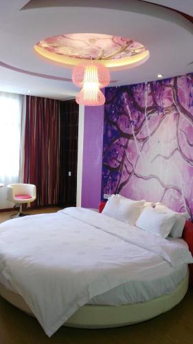 ein Schlafzimmer mit einem großen Bett mit einer lila Wand in der Unterkunft Thank Inn Chain Hotel Henan Xinyang Train Station Gongqu Road in Xinyang