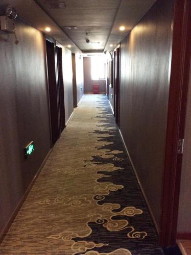 długi korytarz z dywanem na podłodze budynku w obiekcie Thank Inn Chain Hotel Beijing Shunyi District New International Exhibition Center Airport w mieście Houshayu