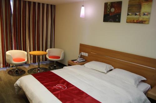 a hotel room with a bed and two chairs at Thank Inn Chain Hotel Jiangsu Huaian Lianshui Dongding in Paifang