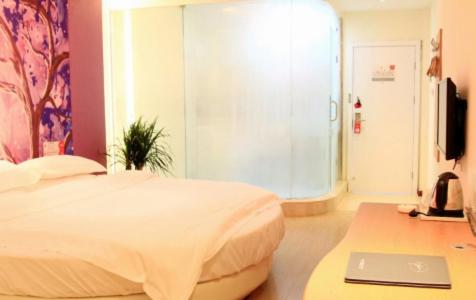a bedroom with a bed and a desk with a laptop at Thank Inn Chain Hotel Henan Xinyang Train Station Gongqu Road in Xinyang