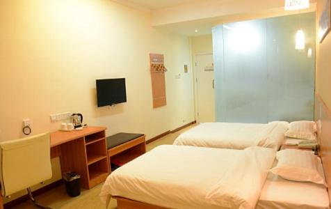 a room with two beds and a desk and a television at Thank Inn Chain Hotel Henan Xinyang Train Station Gongqu Road in Xinyang