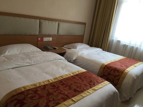 a hotel room with two beds and a window at JUNYI Hotel Shandong Zaozhuang Shanting District Xinyuan Road in Zaozhuang