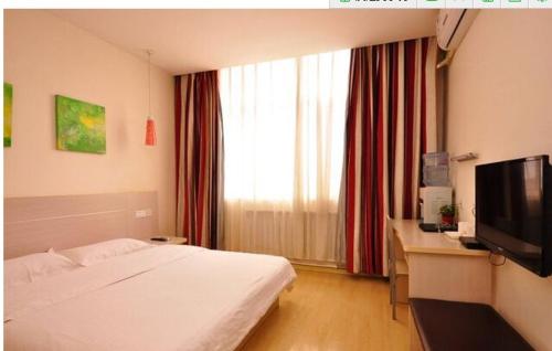 a bedroom with a bed and a desk and a television at Thank Inn Chain Hotel Shandong Dezhou South City in Dezhou