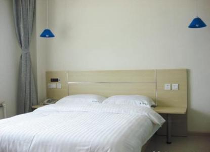 a bedroom with a white bed and a desk at Thank Inn Chain Hotel Shandong Qingdao Development Zone Lingzhushan in Qianwan