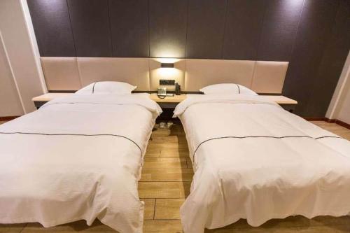 a room with two beds and a table with a lamp at Thank Inn Plus Hotel Hebei Tangshan Road South District Train Station in Tangshan