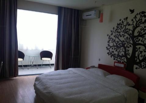 a bedroom with a bed and a window and a table at Thank Inn Chain Hotel Shandong Tengzhou Train Station Wentian Squre in Tengzhou