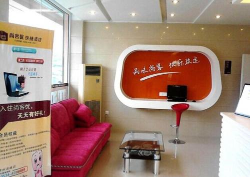 a living room with a red couch and a tv at Thank Inn Chain Hotel Shandong Dezhou South City in Dezhou