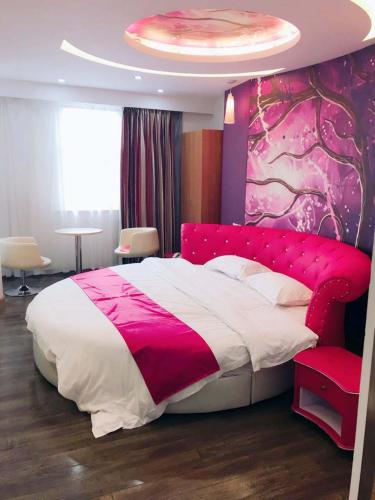 um quarto com uma cama rosa e branca e uma parede rosa em Thank Inn Plus Hotel Jiangsu Taizhou Taixing Jingjiang Primary School em Taixing