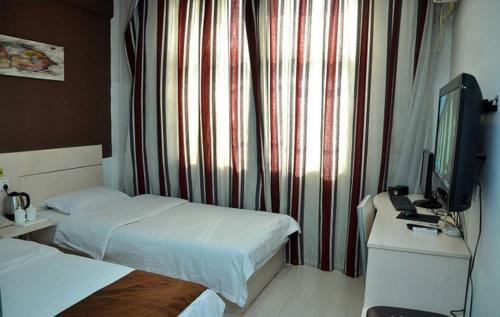 um quarto de hotel com duas camas e uma televisão em Thank Inn Chain Hotel Fei Town Jianshe Road em Feixian