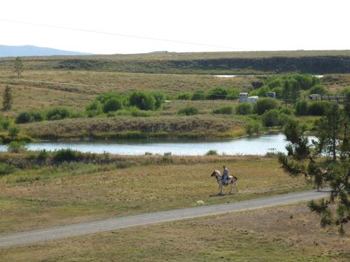 a person riding a horse on a road next to a river at Eagle Ridge Ranch in Island Park