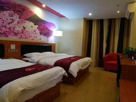 ein Hotelzimmer mit zwei Betten und einem Gemälde an der Wand in der Unterkunft Thank Inn Chain Hotel Zhejiang Huzhou Changxing Town Qingfang City in Jiapu